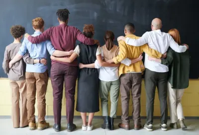 A diverse group standing arm in arm with their backs to the camera, illustrating diversity targets