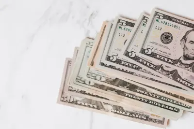 Fanned dollar bills of various denominations on a marble surface, illustrating salary increase budgets