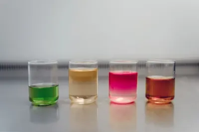 Four laboratory beakers holding different coloured liquids, illustrating life sciences hiring demand