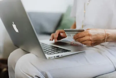 Person typing on a laptop while holding a payment card, illustrating trust in online shopping