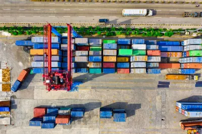 Aerial view of a shipping container yard with a gantry crane, illustrating AI making logistics more sustainable