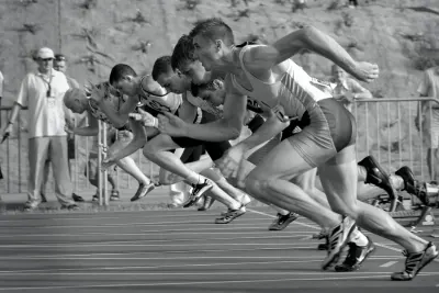Sprinters exploding off the starting blocks on a running track, illustrating free competition and acts of authority