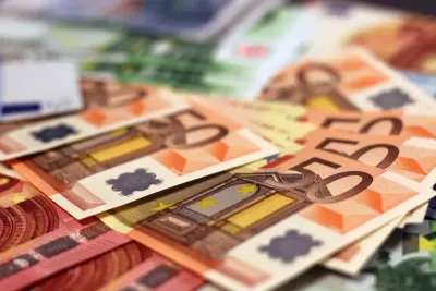 Close-up of scattered fifty-euro banknotes, illustrating businesses that delay investment to conserve cash