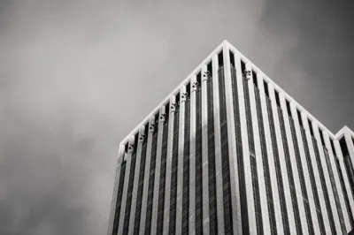 A tall office tower viewed from below in black and white, illustrating what UK financial institutions spend on financial crime