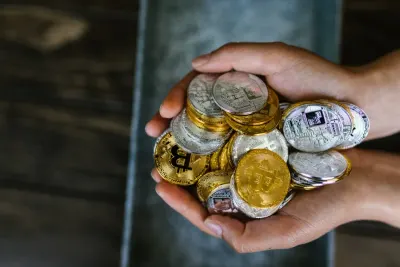 Cupped hands holding a pile of gold and silver crypto coins, reflecting growing crypto adoption