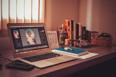 Laptop showing photo editing software on a home desk beside a calendar and notebook, illustrating freelancers boosting employment