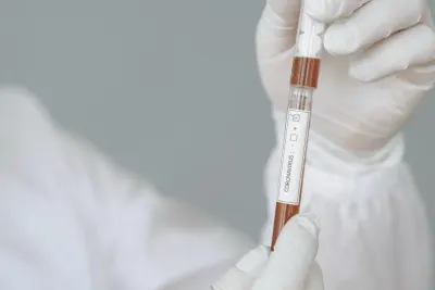 A gloved hand holding up a blood sample vial labelled coronavirus, illustrating debate over immunity certificates
