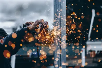 A welder working amid bright sparks on a construction site, reflecting demand in engineering hiring