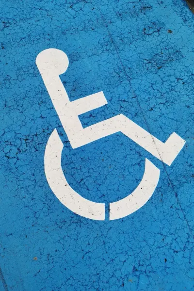 Wheelchair accessibility symbol painted on a cracked blue surface, illustrating the disability employment gap