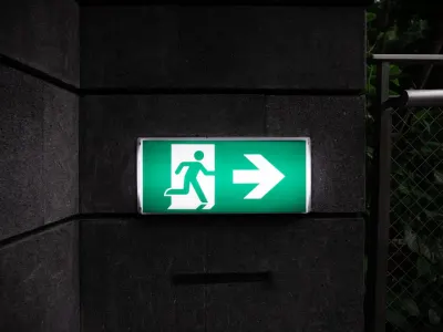 An illuminated green exit sign on a wall, symbolising the talent exodus as workers plan to quit