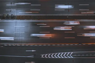 Aerial view of blurred traffic streaming along a motorway at dusk, illustrating fines for speeding offences