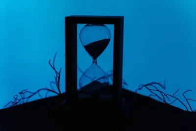 Hourglass silhouette against a blue backdrop with bare branches, symbolising the cost of delayed compliance automation