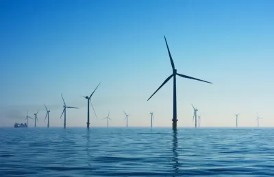 Offshore wind turbines standing in calm blue water, representing growth in the renewable energy market