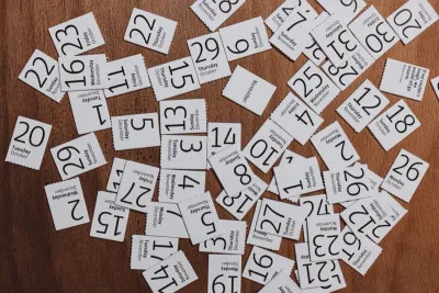 Scattered daily calendar date cards spread across a wooden table, illustrating attendance bonuses