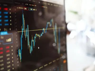 A close-up of a financial trading screen showing volatile currency charts, reflecting the mood of anxious investors