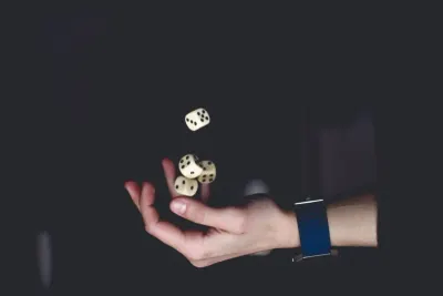 A hand tossing dice in darkness, symbolising the gamble of poor risk management