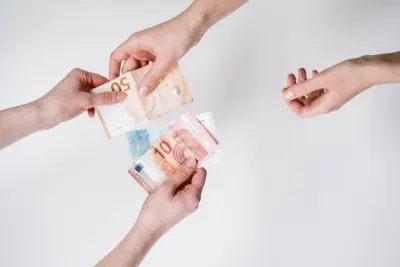 Hands exchanging euro banknotes against a white background, illustrating price discrimination of customers