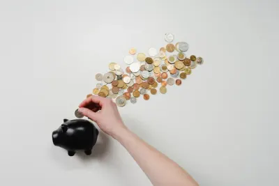 A hand dropping a coin into a piggy bank beneath an arrow of scattered coins, reflecting changing financial habits